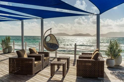 a deck with chairs and a swing and the ocean at Aurora Anguilla Resort & Golf Club in Rendezvous Beach