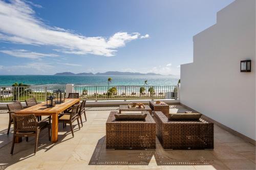a patio with a table and chairs and the ocean at Aurora Anguilla Resort & Golf Club in Rendezvous Beach