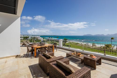 a balcony with a table and chairs and the ocean at Aurora Anguilla Resort & Golf Club in Rendezvous Beach