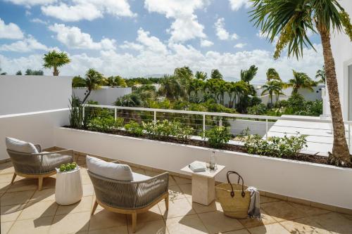 a balcony with chairs and a view of palm trees at Aurora Anguilla Resort & Golf Club in Rendezvous Beach