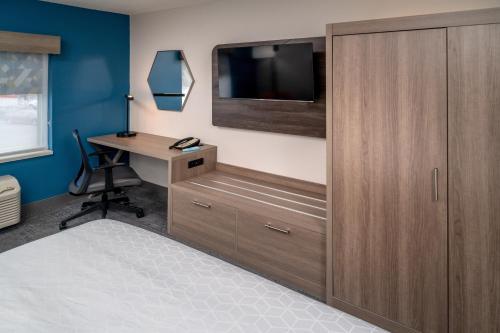a bedroom with a desk and a tv on a wall at Holiday Inn Express - Charleston/Kanawha City by IHG in Charleston