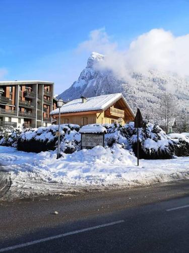 une maison avec une montagne en arrière-plan et de la neige dans l'établissement Appartement rénové avec parking plein centre, à Samoëns
