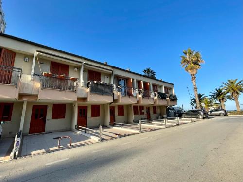 a building with red doors and balconies on a street at {Perla d'aMare ~ Zaffiro} Appartamento sul mare in San Benedetto del Tronto