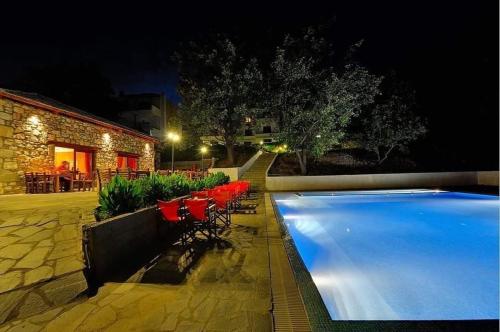 a swimming pool with red chairs next to a building at TSIGOURA VERDE RESORT in Mikrós Prínos