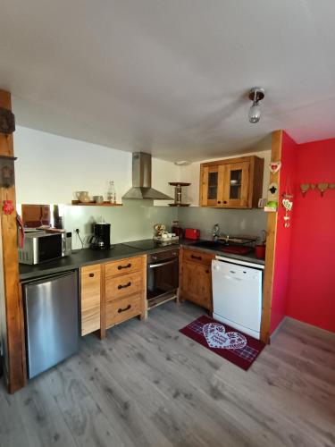 una cocina con armarios de madera y una pared roja en Chez ma Grand-mère, en Saint-Félix