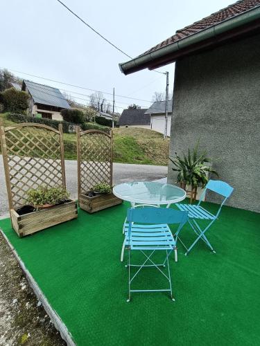 een patio met een tafel en stoelen op een groene verdieping bij Chez ma Grand-mère in Saint-Félix