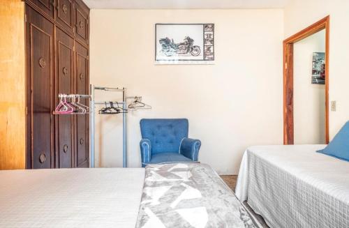 uma cadeira azul sentada ao lado de uma cama num quarto em Suite com ar em Jaú