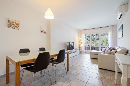 a living room with a table and chairs and a couch at Hauzify I Apartament Bòvila Mar in S'Agaro