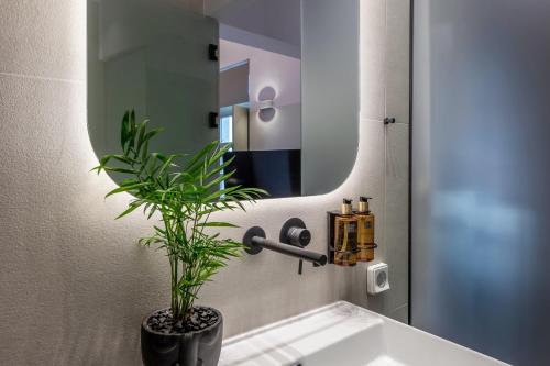 a bathroom with a sink with a mirror and a plant at Octavia Rooms in Korinthos