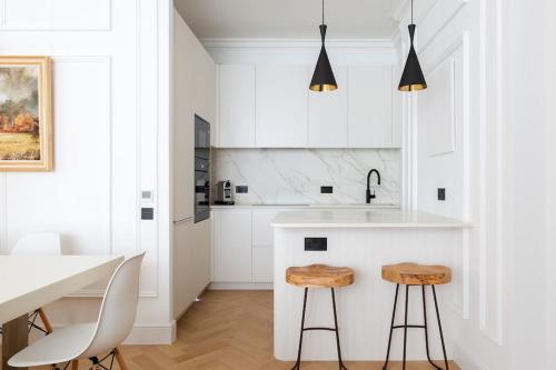 a white kitchen with white cabinets and stools at Knightsbridge - Sumptuous Flat - Hyde Park in London