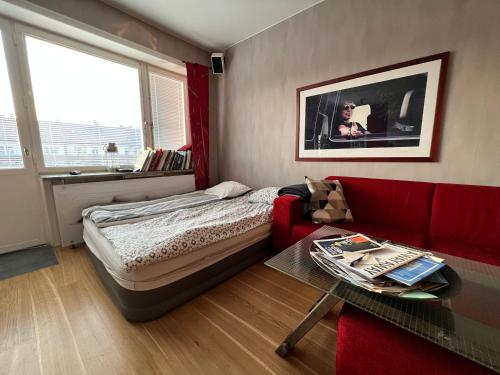 ein Schlafzimmer mit einem Bett und einem roten Sofa in der Unterkunft Etage flat Stockholm Stora Essingen in Stockholm