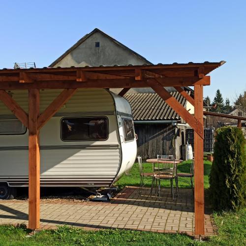 una caravana estacionada bajo una pérgola de madera en Camping U Mani, en Wiżajny