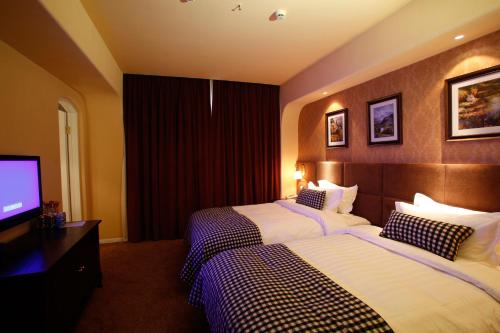 a hotel room with two beds and a flat screen tv at Aoting Garden Hotel in Chengdu