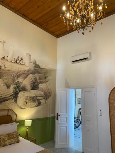 a bedroom with a painting on the wall and a chandelier at Dar Alice in Soûr