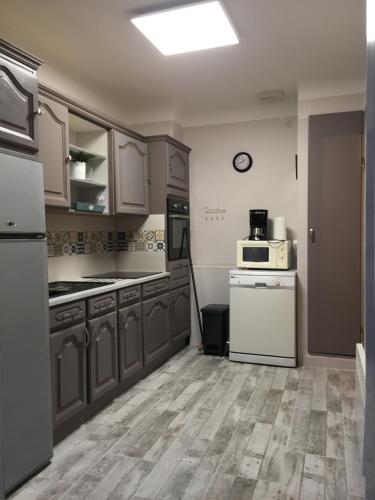 une cuisine avec des placards gris et des appareils blancs dans l'établissement maison 50m de la mer, à Pornichet
