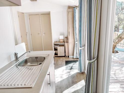 une cuisine blanche avec un évier et une fenêtre dans l'établissement 3 bedroom Chalets Camping Leï Suves - JoyCasa, à Roquebrune-sur Argens