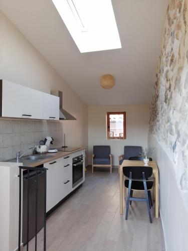 une cuisine avec des armoires blanches et une table et des chaises dans l'établissement Zofia appartements - T2 en duplex avec terrasse, à Moustiers-Sainte-Marie
