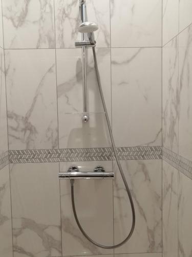La salle de bains est pourvue d'une douche avec un tuyau et de carrelage blanc. dans l'établissement Zofia appartements - T2 en duplex avec terrasse, à Moustiers-Sainte-Marie