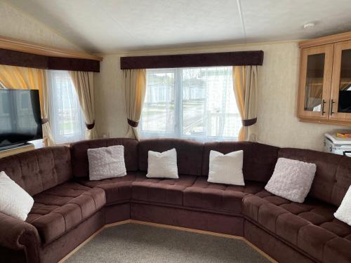 a living room with a brown couch with pillows at TM5 Golden Palm Resort in Chapel Saint Leonards
