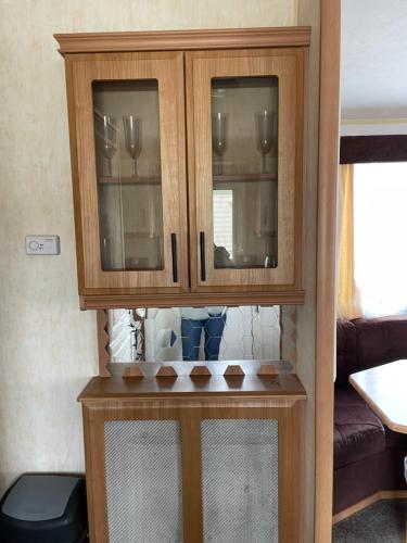 a wooden cabinet with two glass doors on a table at Golden Palm Resort TM5 in Chapel Saint Leonards