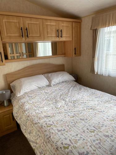 a bedroom with a large bed with wooden cabinets at Golden Palm Resort TM5 in Chapel Saint Leonards