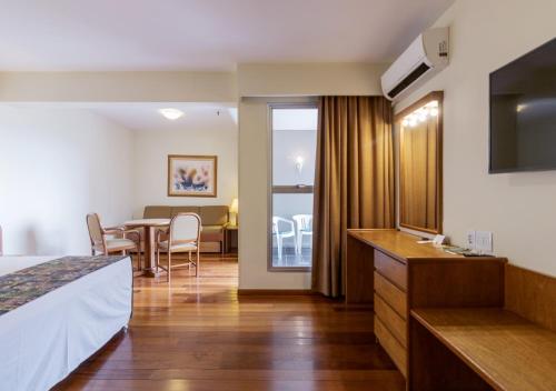 a hotel room with a bed and a table with chairs at Ritter Hotéis in Porto Alegre