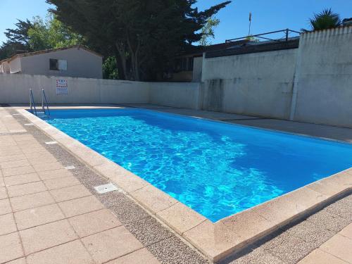 une grande piscine bleue à côté d'une clôture dans l'établissement Résidence LA GRAND VOILE, à Sainte-Marie-la-Mer