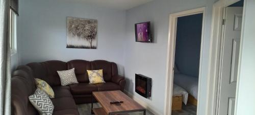 a living room with a brown couch and a table at Grenada Garden Lodges in Ingoldmells