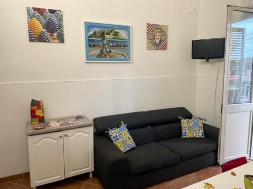 a living room with a black couch and pictures on the wall at Ninni Mondello House in Mondello