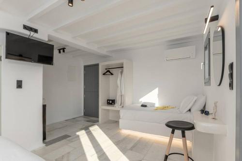 a white room with a bed and a stool at FK Luxury Suites - Orkos Beach in Mikri Vigla