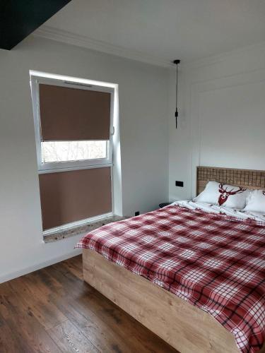 a bedroom with a bed with a plaid blanket and a window at Mona Luxury Apartment in Lębork