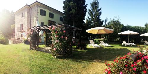 a house with a yard with chairs and an umbrella at San Processo Agriturismo in Castel del Piano