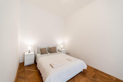 Exclusive apartment near Kafka's head في براغ: غرفة نوم بيضاء بسرير ابيض ومصباحين