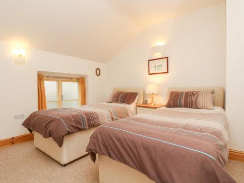 a bedroom with two beds and a window at Apple Cottage in Crediton