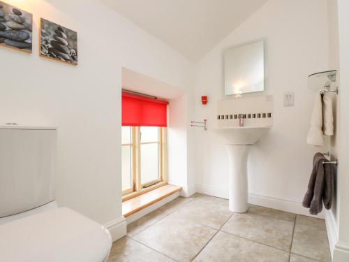 ein Bad mit einem Waschbecken und einem Fenster in der Unterkunft Apple Cottage in Crediton