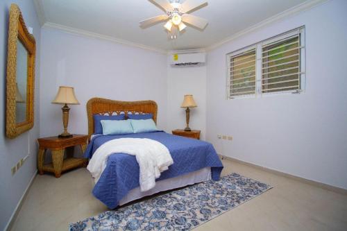 a bedroom with a bed and a ceiling fan at Crystal Cove Oceanfront/ 2 bedroom Condo in Ocho Rios
