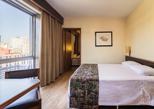 a hotel room with a bed and a large window at Ritter Hotéis in Porto Alegre