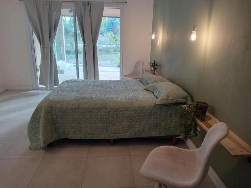 1 dormitorio con 1 cama con 2 sillas y una ventana en Casa Tierra Verde Oliva en Luján de Cuyo