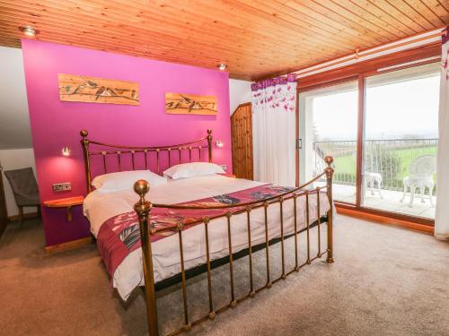 1 dormitorio con 1 cama con pared de color rosa en Higher Kernick Farm en Launceston