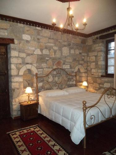 una camera con letto e parete in pietra di Hotel Vila Aleksander a Berat