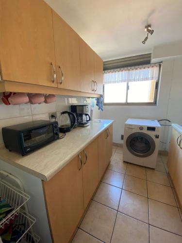 a kitchen with a microwave and a washing machine at Rincones del Placer, un lugar repleto cariño in Valparaíso