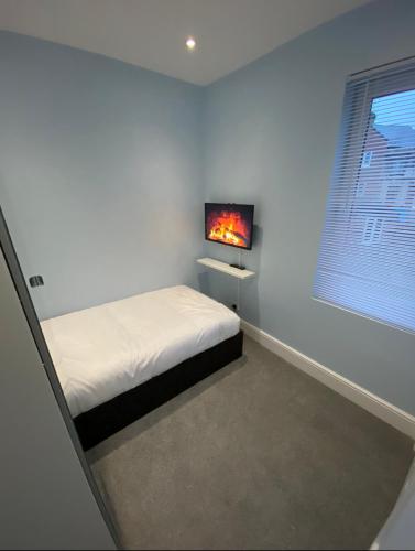 a bedroom with a bed and a tv on the wall at Beckett Guest House in Barnsley