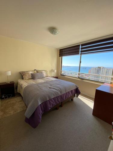a bedroom with a large bed and a large window at Rincones del Placer, un lugar repleto cariño in Valparaíso