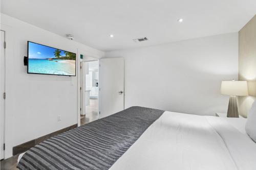 a white bedroom with a bed and a tv on the wall at Upscale Modern Villa Private w Terrace in Bahia Mar Beachfront Resort, Heated Pool! in South Padre Island