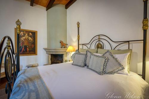 a bedroom with a white bed with pillows and a fireplace at San Rafael Hotel in Antigua Guatemala