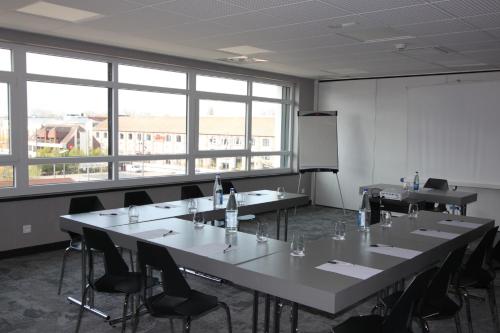 a conference room with tables and chairs and windows at The Originals Boutique, Hôtel d'Alsace, Strasbourg Sud in Illkirch-Graffenstaden