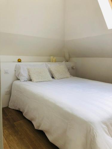 a white bed with two pillows on top of it at Esmée - Havre de Charme sous les Toits in Perros-Guirec