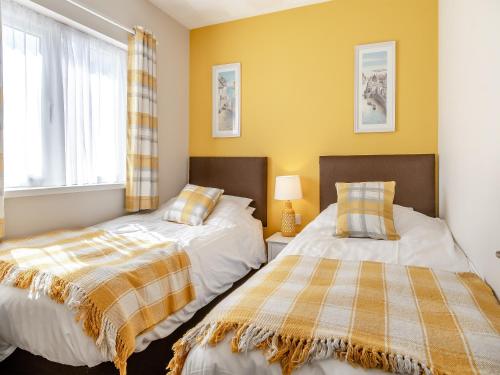 2 camas en un dormitorio con paredes amarillas en Uk43574 - Fern Cottage, en Begelly