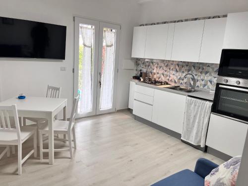kuchnia z białymi szafkami i stołem z jadalnią w obiekcie Casa sul Mare Formia Con una Splendida Terrazza w mieście Formia