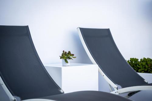 two black chairs sitting next to a table with a plant at Trieris Villa & Suites in Fira
